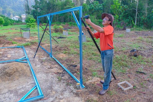 Zahradníci používají bezdrátový šroubovák a vodováhu při stavbě dětských staveb z c kanálové oceli v zahradě. - Fotografie, Obrázek