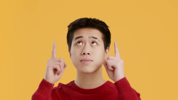 Chinese zeigt mit den Fingern nach oben Werbung für etwas über gelbem Hintergrund - Filmmaterial, Video
