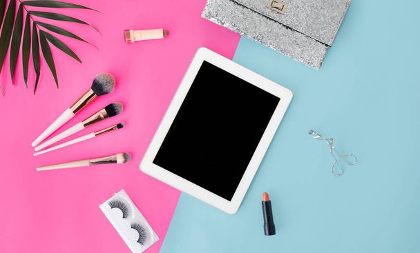 Κοριτσίστικη σύνθεση με digital tablet και διάφορα προϊόντα μακιγιάζ σε μπλε και ροζ φόντο, top view, mockup - Φωτογραφία, εικόνα