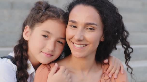 Portrait hispanique famille brunette jeune mère professeur nounou maman maman et petite fille mignonne petit enfant écolière élève fille enfant câlin câlin embrasser câlin regardant caméra à l'extérieur - Séquence, vidéo