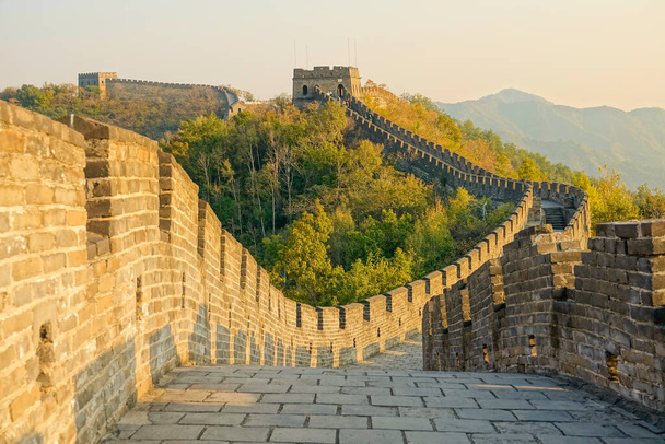 Blick auf den Kopfsteinpflasterweg auf der Chinesischen Mauer bei goldenem Sonnenuntergang. - Foto, Bild