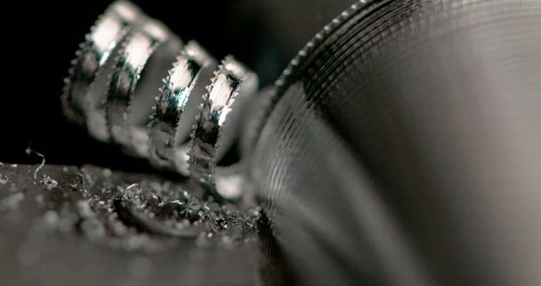MACRO: Lange spiralen van overtollig metaal worden gemaakt als draaibank tool creëert een schroef. - Foto, afbeelding