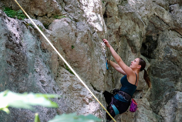 Zaostřená žena hledá puklinu ve stěně při lezení na skálu - Fotografie, Obrázek