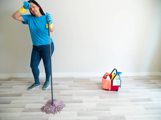 Beyaz bir kadın bir şişe su fırçasıyla temizlik yapıyor ve evini temizleme eldiveni ve mendilleriyle süpürüyor. - Fotoğraf, Görsel