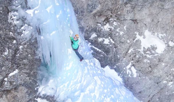 Mulher colocando cuidadosamente seus machados de gelo enquanto subia uma cachoeira gelada - Foto, Imagem