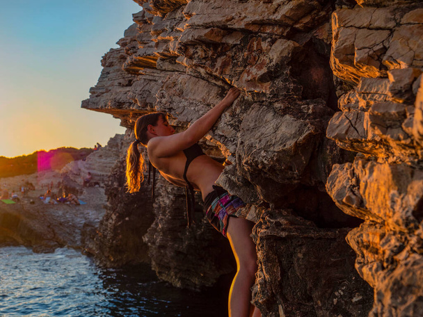 CERRAR: Chica activa escalada en la playa en una soleada noche de verano. - Foto, imagen