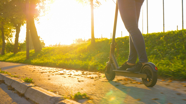 NIEDERENGEL: Junge Frau in Jeans fährt bei schönem Sonnenaufgang Elektroroller. - Foto, Bild