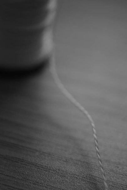 Spool of thread on the table closeup. BW photo - Photo, Image