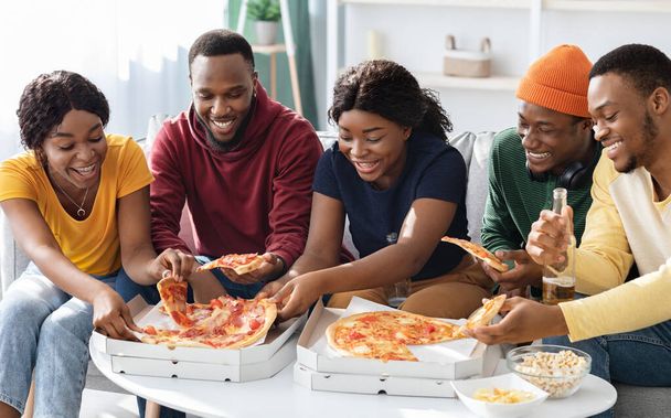 Positivo negro hombres y mujeres comiendo pizza en casa - Foto, imagen