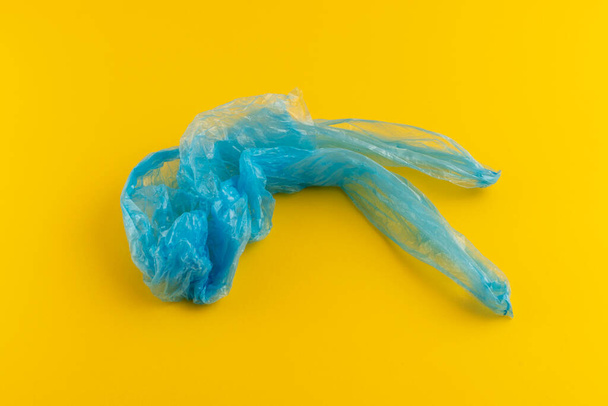 Голубой мятый пластиковый пакет. На желтом фоне.  - Фото, изображение