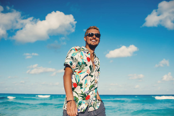 Denizde ya da okyanus arka planında Hawaii gömleği giyen çekici bir adam. - Fotoğraf, Görsel