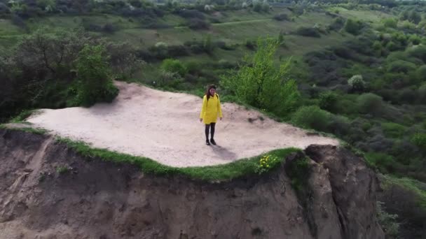 Frau steht am Rande eines Abgrunds am Berg und winkt mit der Hand und gibt Luftkuss - Filmmaterial, Video