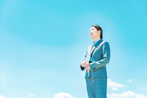 Jeune femme d'affaires asiatique debout contre le ciel bleu - Photo, image