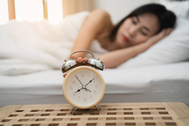 Young woman sleeping and alarm clock in the bedroom at home - Photo, Image