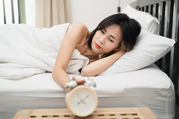 Young woman sleeping and alarm clock in the bedroom at home - Foto, afbeelding
