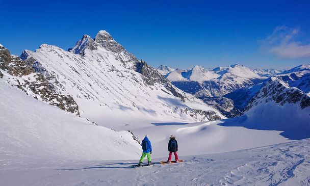 Δύο νεαροί snowboarders παρατηρούν βουνά πριν από την επιτάχυνση κάτω ανέγγιχτη - Φωτογραφία, εικόνα