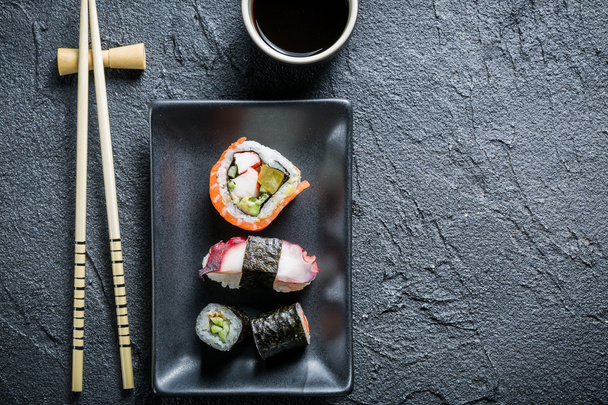 Sushi served on a black ceramic with soy sauce - Foto, imagen