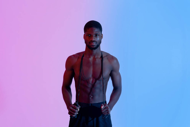 Portrait of motivated black guy with jumping rope posing in neon light. Active lifestyle concept - Φωτογραφία, εικόνα