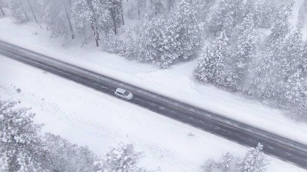 Drone: ripresa cinematografica di un'auto che percorre una strada vuota durante una tempesta di neve - Foto, immagini