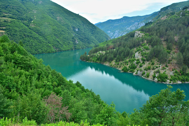 Las aguas turquesas del lago Koman rodeadas de verdes acantilados y gargantas - Foto, Imagen