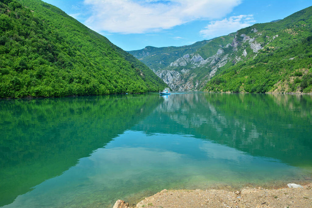 As águas azul-turquesa do Lago Koman rodeado por falésias verdes e desfiladeiros. Uma balsa navegando no lago. - Foto, Imagem