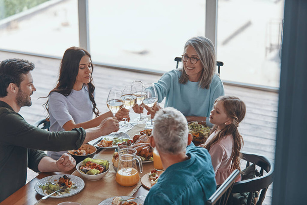 Happy multi-generation family toasting and smiling while having dinner together - Valokuva, kuva