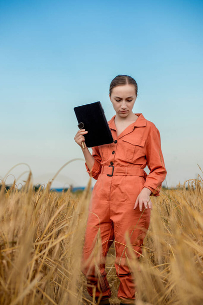 Woman caucasian technologist agronomist with tablet computer in the field of wheat checking quality and growth of crops for agriculture. Agriculture and harvesting concept - Foto, Imagen