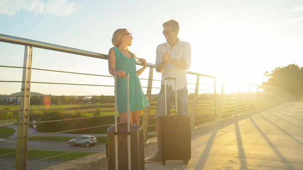 レンズフレア:若い新婚旅行は興奮して晴れた日に空港シャトルを待っています - 写真・画像