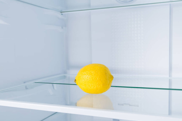 λεμόνι στο ψυγείο σε γυάλινο ράφι, σε λευκό φόντο - Φωτογραφία, εικόνα