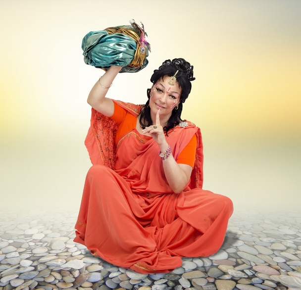 Mujer sentada en sari naranja sosteniendo turbante
 - Foto, imagen