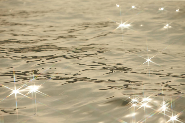 Yksityiskohta auringonvalosta kimaltelevassa meressä. kipinöitsijä vedessä - tausta. merivesi auringon häikäisyllä ja aaltoilulla. Voimakas ja rauhallinen luontokäsite. - Valokuva, kuva