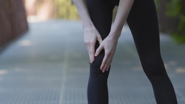 Mulher atlética magro irreconhecível em pernas pretas atleta corredor feminino corredor tendo lesão dolorosa no joelho durante o exercício de jogging no parque ao ar livre, condição do corpo dor dor problema ligamento articular - Filmagem, Vídeo