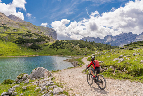 mooie seniorenvrouw op haar elektrische mountainbike in het Fanes hoogdal, onderdeel van natuurpark Fanes-Sennes-Braies in de Alta Badia Dolomieten, Zuid Tirol en Trentino, Italië - Foto, afbeelding