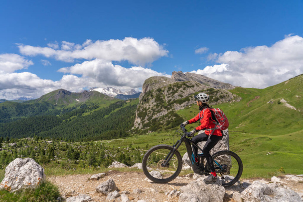 mulher sênior muito ativa montando sua bicicleta de montanha elétrica até Valparola Pass no Alta Badia Dolomites, Tirol do Sul e Trentino, Itália - Foto, Imagem