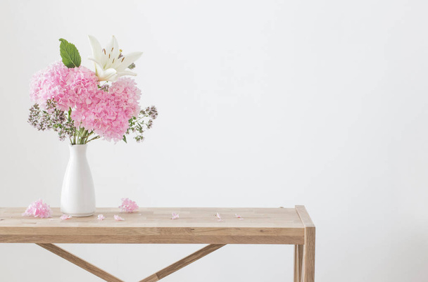 white and pink flowers in white vase on wooden shelf - Φωτογραφία, εικόνα