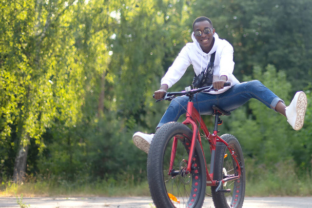A happy African-American man rides a bicycle in the park. - Foto, immagini