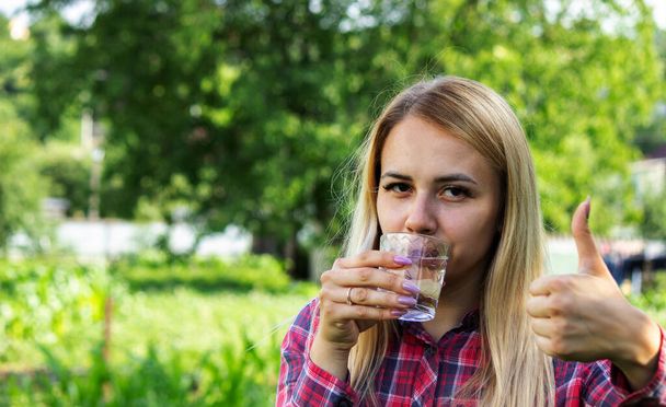Mädchen trinkt Wasser aus einem Glas, draußen. Selektiver Fokus - Foto, Bild