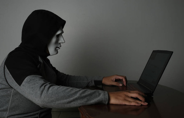 Een lage belichting foto van hacker met laptop inzicht. Hacken en cyber security bedreiging concept. - Foto, afbeelding