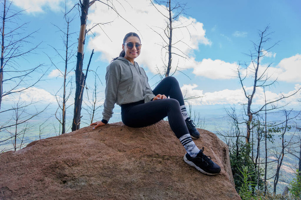 Una joven hispana sentada en una roca y disfrutando de la hermosa naturaleza - Foto, Imagen