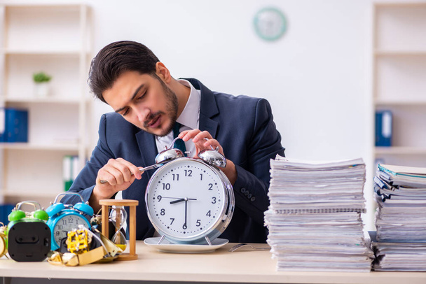 Young businessman employee eating alarm-clock - Photo, Image