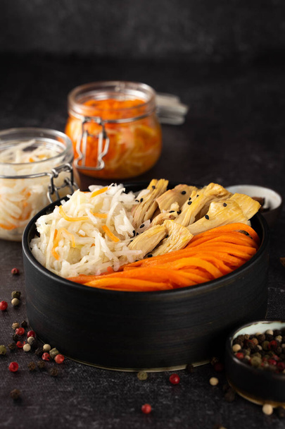 Choucroute fermentée de village maison, et carotte coréenne, asperges. Salade végétalienne dans un bol en céramique noire. Les probiotiques intègrent le concept des aliments santé. Complément et adaptogènes. Superfood, vue de dessus - Photo, image