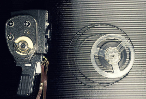 Old amateur movie camera and reel of film stock on black background - Photo, image