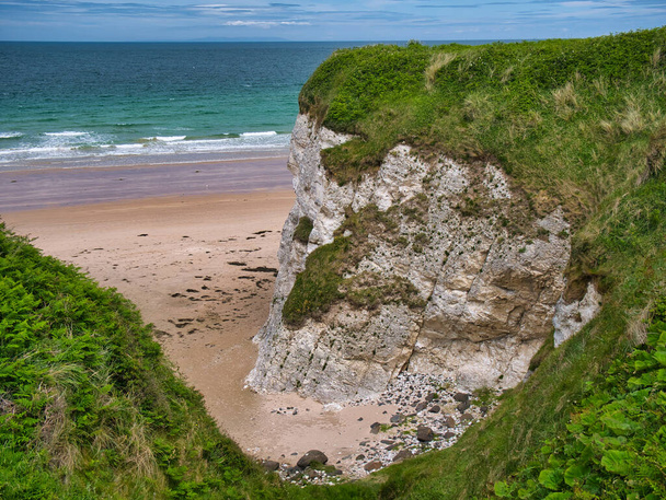 Küstenfelsen mit exponierten Schichten in der Nähe von Portrush auf dem Damm-Küstenpfad - diese Felsen sind von der überwinternden Grünsand- und ulsterweißen Kalksteinformation - Kreide und Sandstein - Foto, Bild