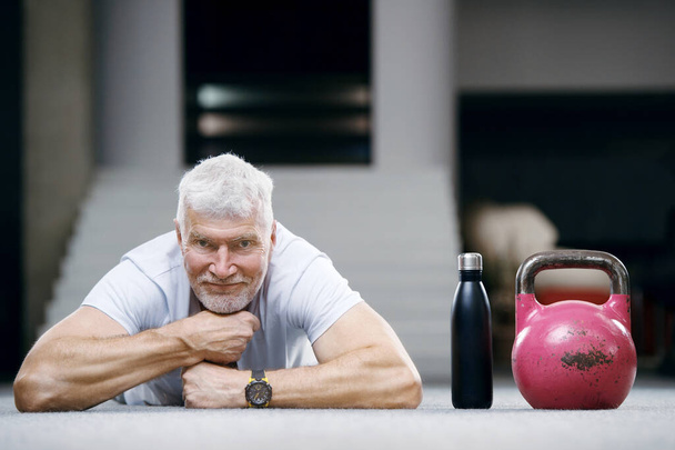 good looking gray haired senior man in white shirt with a water bottle. Sport and health care concept - Fotoğraf, Görsel
