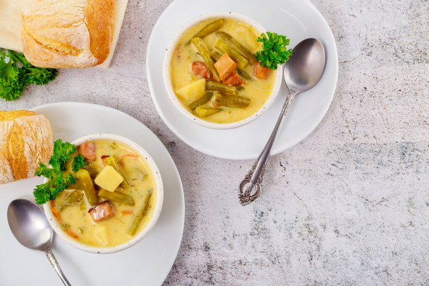 Домашний овощной суп с нарезанным зеленым горошком, картошкой и мясом. Вид сверху. - Фото, изображение