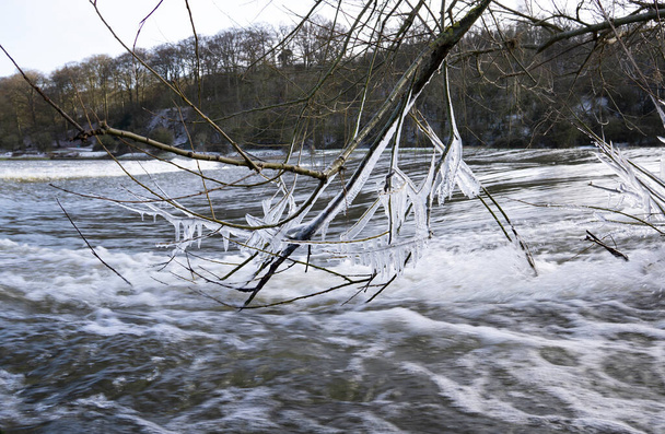 Ледяные сосульки образуются над быстротекущей рекой - Фото, изображение