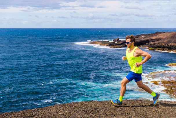 Trail runner athlete man ultra running on rocky trail path with ocean water nature landscape. Active lifestyle of training in nature - Foto, imagen