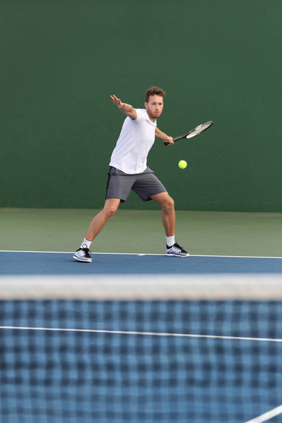 ハードコートでネット上で前手ボールを打つプロのテニス選手選手の選手の男はテニスの試合をプレイ。スポーツゲームフィットネスライフスタイル - 写真・画像