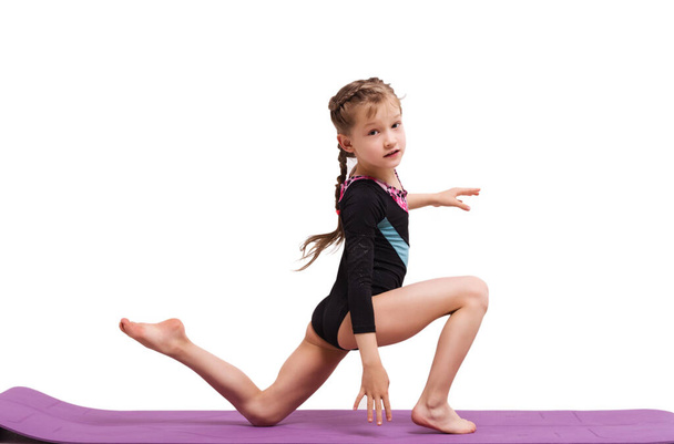 Cute girl dziecko co gimnastyczne ćwiczenia przeciwko białym. - Zdjęcie, obraz