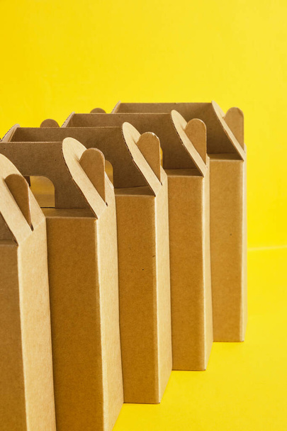 several cardboard boxes on a yellow background, boxes for a gift or product delivery without a logo, blank packaging for your design copy space - Foto, Imagem